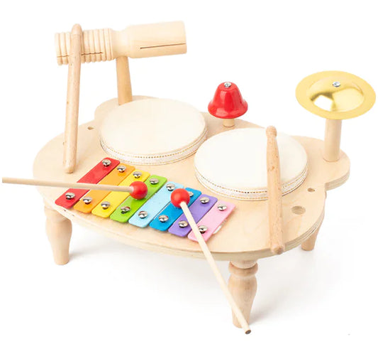 A Montessori-inspired wooden drum set with two drums, a cymbal, a red bell, and a colorful xylophone. 